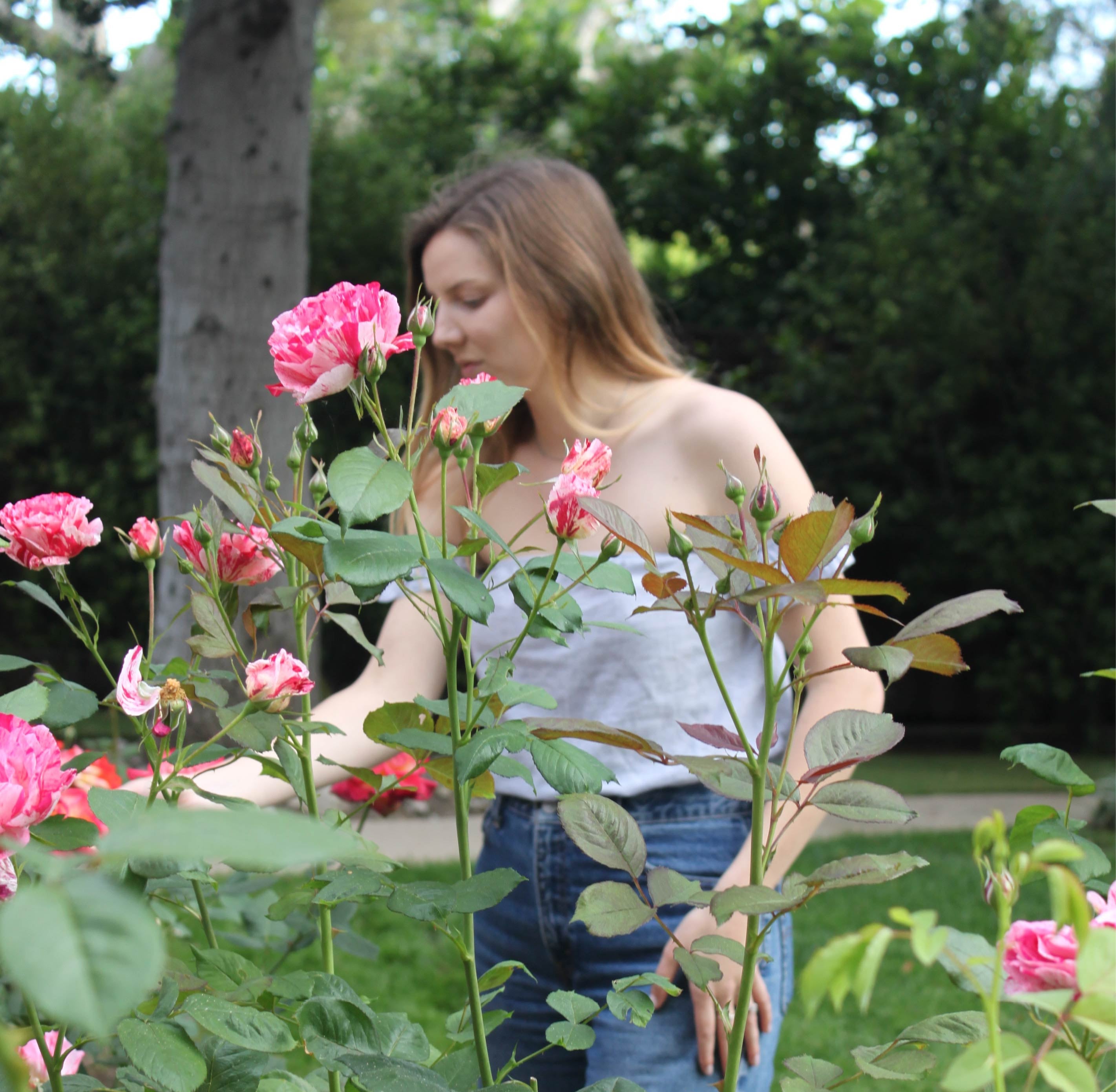 Aubri, Founder of Rebrand Skincare standing among pink roses in a garden